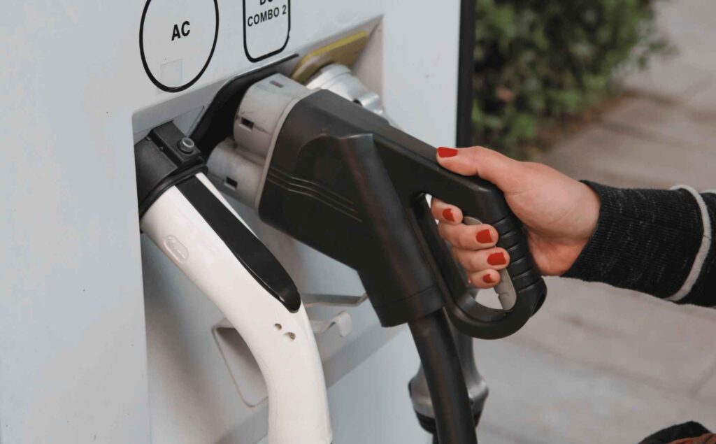 Main branchant un câble sur une borne de recharge, représentant la part énergie dans les dépenses d’une flotte automobile et la transition vers les véhicules électriques.