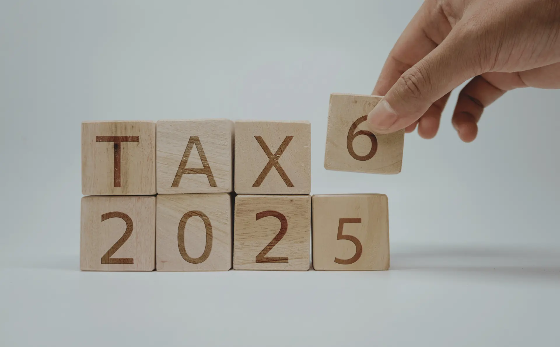 Bloc de bois formant le mot « TAX 2025 », illustrant les nouvelles règles d’exonération fiscale flotte automobile applicables à partir de 2025